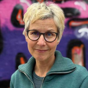 Foto Porträt von Ina Rometsch vor einer Graffitiwand.