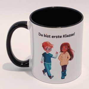 Eine weiße Tasse mit schwarzem Henkel und Innenraum. Darauf abgebildet sind Ella und Tim aus der gleichnamigen Comicreihe mit der Aufschrift "Du bist erste Klasse!" über ihren Köpfen. Die Schrift ist schwarz. Nur der eine i Punkt ist rot. Das Motiv und der Spruch sind auf beiden Seiten jeweils einmal abgedruckt. Die Tasse steht auf weißem Hintergrund und der Henkel zeigt nach links.
